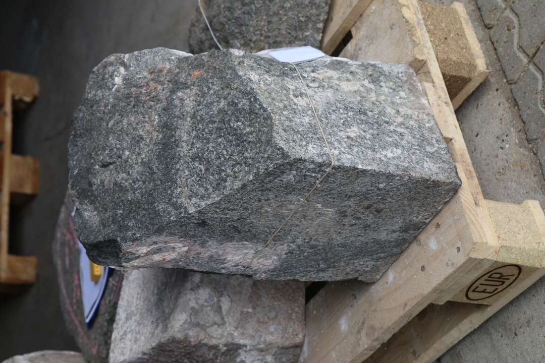 Søjlesokkel af mørk gråblå granit. Største mål: 45 x 31 x 31 cm. Tilhuggede tilnærmelsesvis glatte flader på fire sider. Ene hjørne er brudt af.