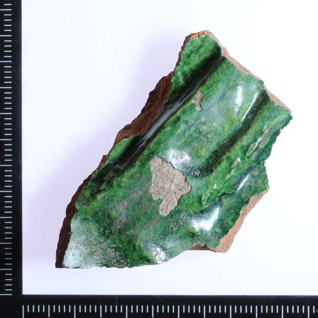 Fragment af hjørne fra kakkel. Spættet grøn glasur.