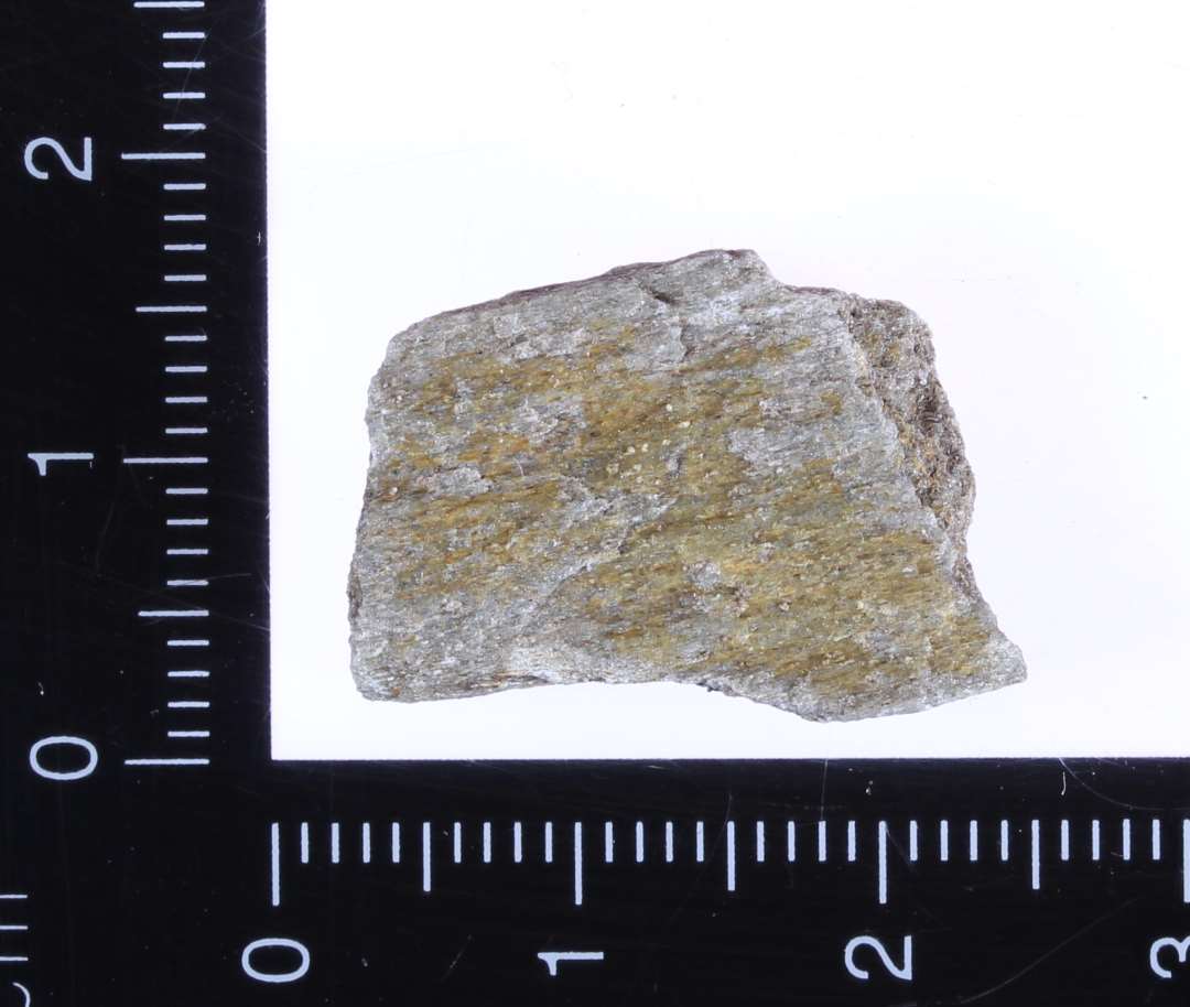 Lille fragment af hvæssesten. Slibeflade på den ene side. 2 x 1,5 x 0,4 cm.
