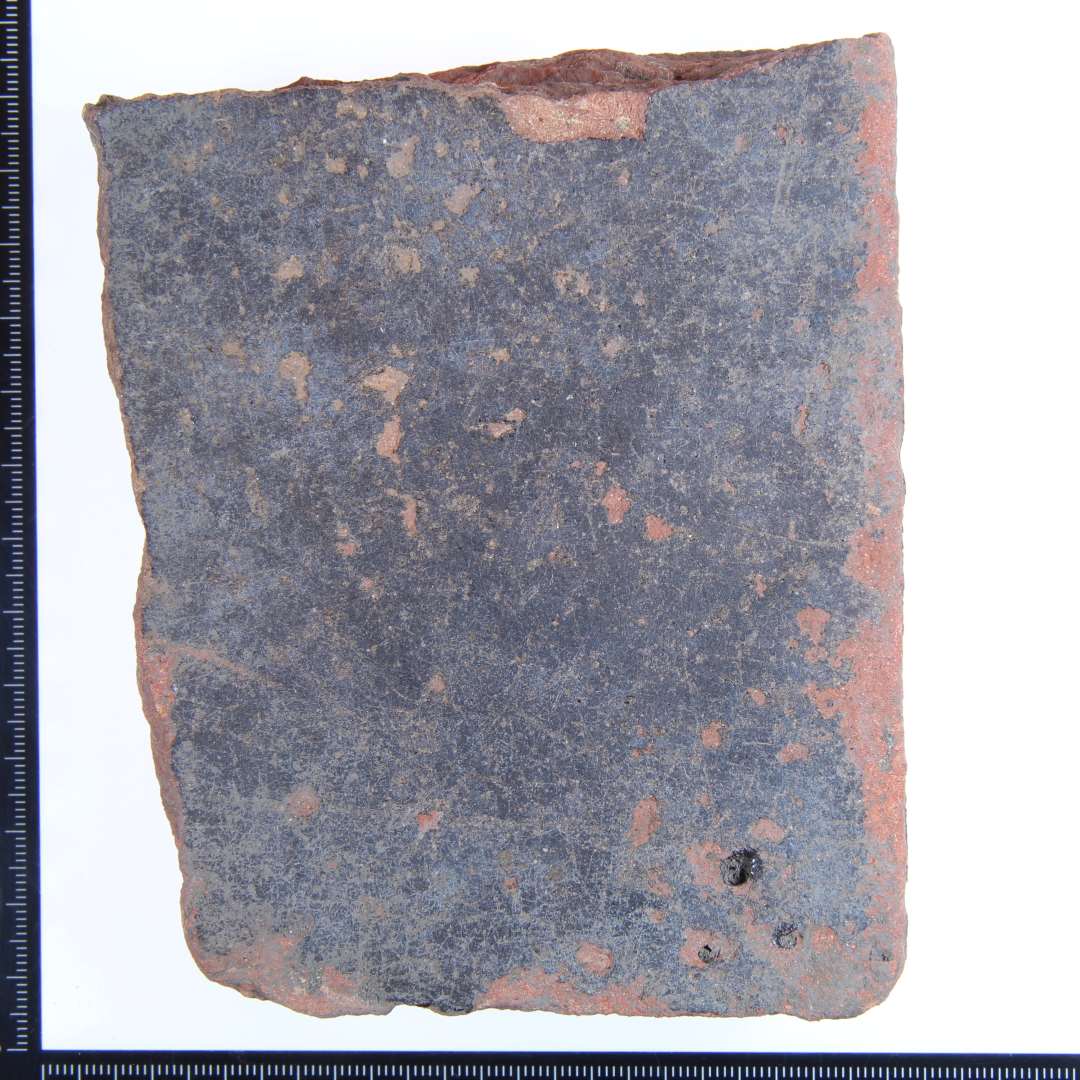 Et rødbrændt hjørne fragment med grøn glasur på oversiden, og på 2 af sidekanterne. Mål:12x8,5x3 cm.