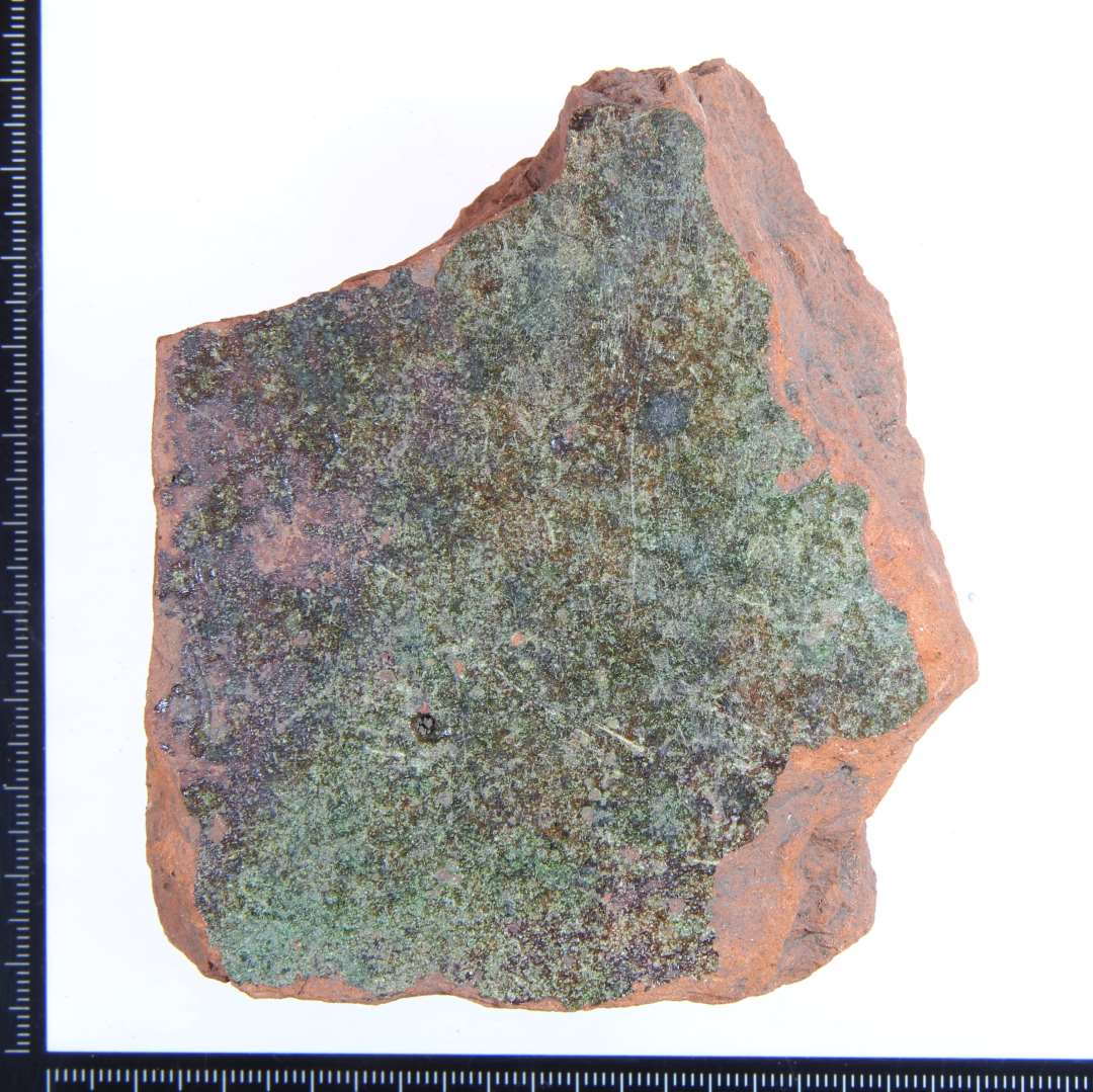Et rødbrændt hjørne fragment af gulvflise med grøn glasur på oversiden. Største mål: 9x8x3 cm.