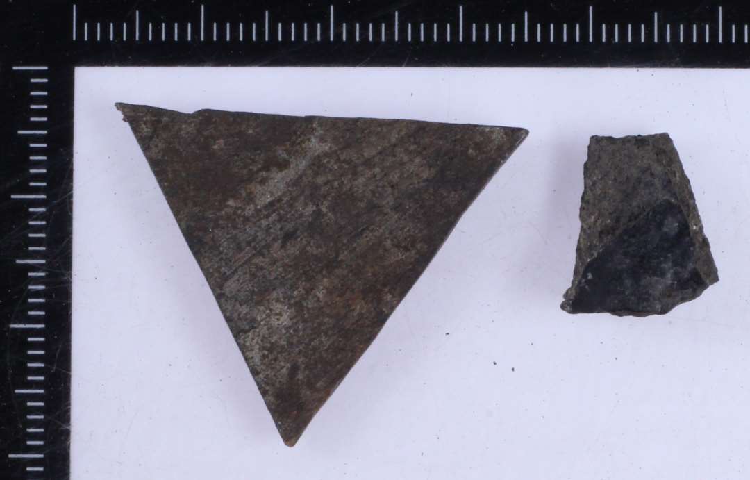 Det ene stykke muligvis skåret/formet som en ligesidet trekant, ca. 3X3X3 cm. Den anden sort/forkullet og fragmenteret.
