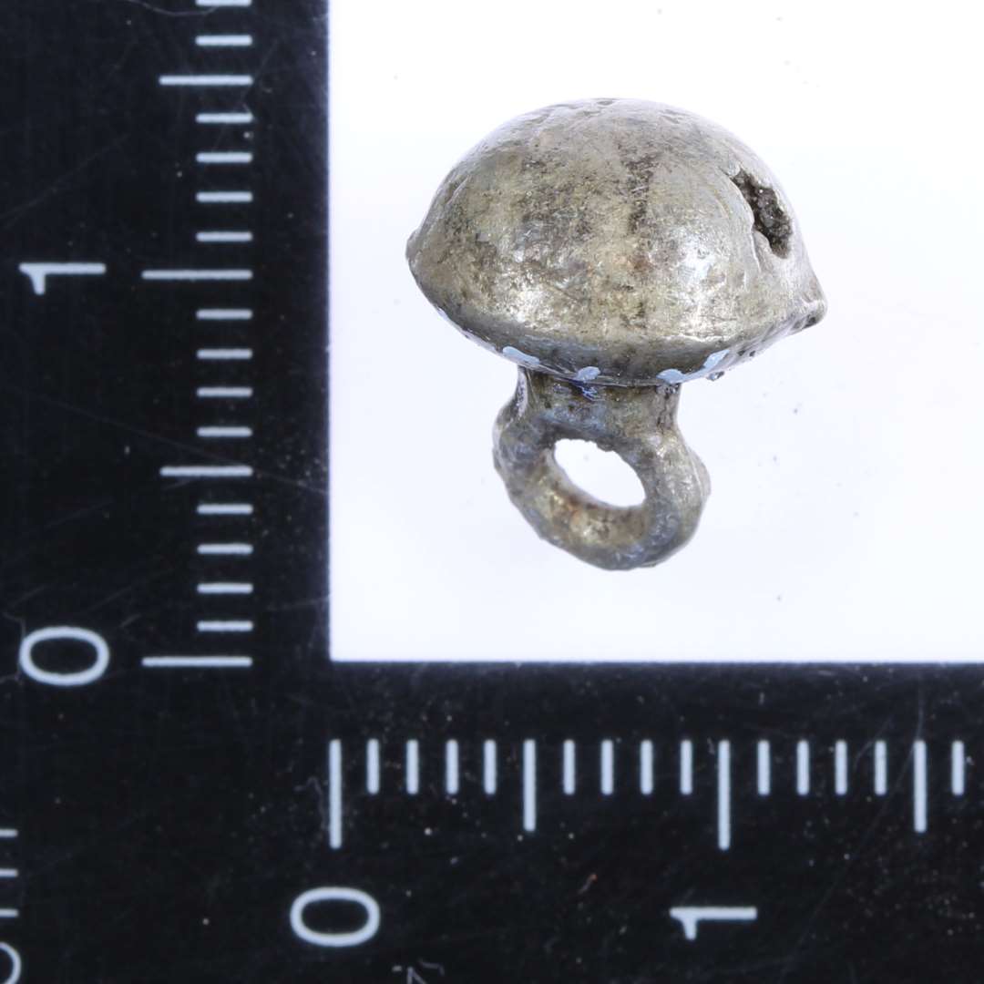 Lille halvkugleformet knap med øsken. diameter: ca 0,9 cm.