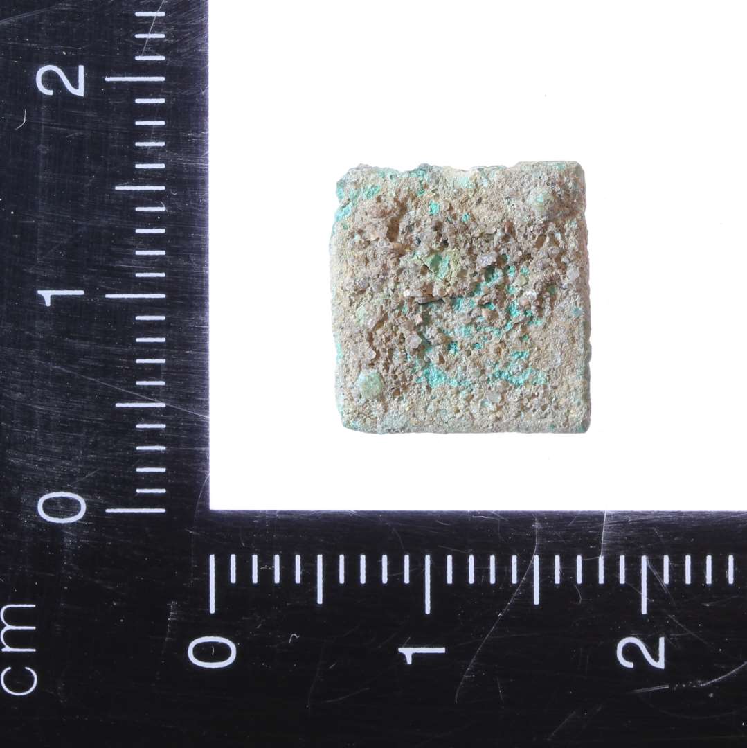 Lillle Kvadratisk nitteplade af kobberlegering. Ca. 1,2x1,2 cm.