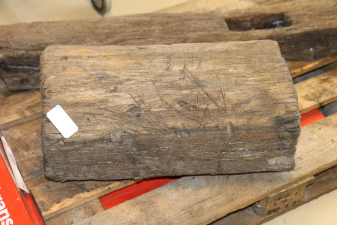 Kraftigt stykke tømmer, tilhugget, kantet yderside med mange hugspor. Måske (sekundær?) huggeblok?. Højde: 57 cm., diameter: 37 cm.