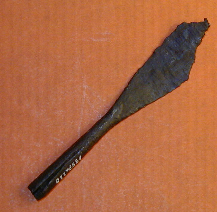Pilespids med rhombe-formet blad, samt dølle. Samlet længde 9,5 cm (spidsen ikke bevaret), bredeste sted på bladet c. 1,7 cm.