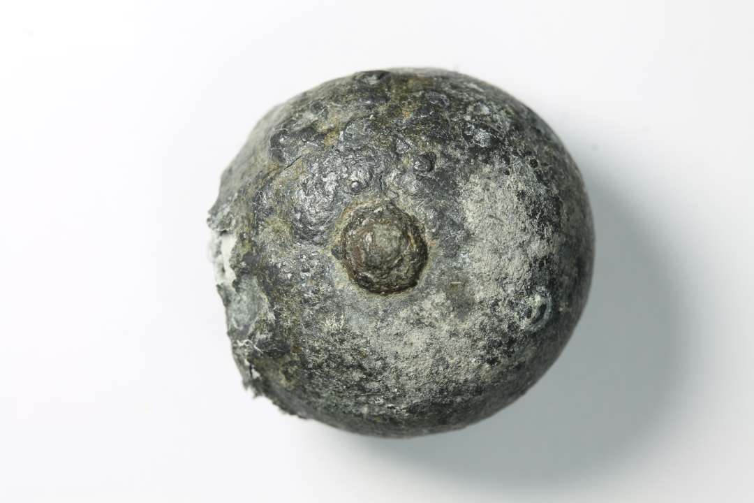 Kugleformet, Ø ca. 1,8-2,2 cm. Lille 'dut' af antagelig jern, stikker frem på den ene side.