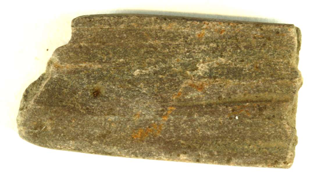 Fragment af hvæssesten. Bred, flad. Mål: 18 x 35 mm.