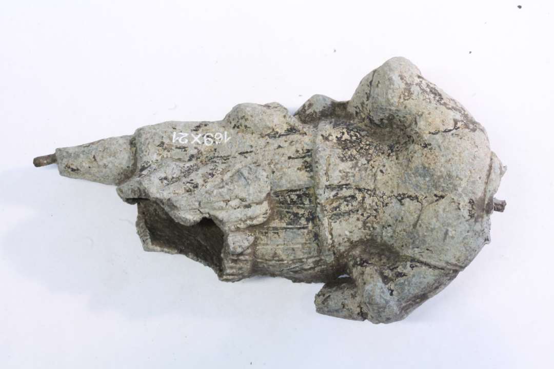 Et fragment af en statuette, som er fremstillet af en grå blylegering, som kan have været bemalet. Statuetten forestiller en mand i renæssancedragt. 
Længde: 12 cm. 
