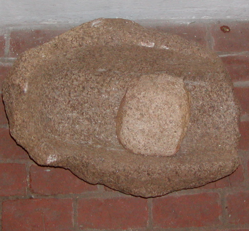 Komplet skubbekværn af bjergart ('granit'). Målet ca. 67x50x30 cm. Kraftig hulning, ca. 14 cm dyb og 31 cm bred. Fortsætter ud gennem den ene ende af stenen.