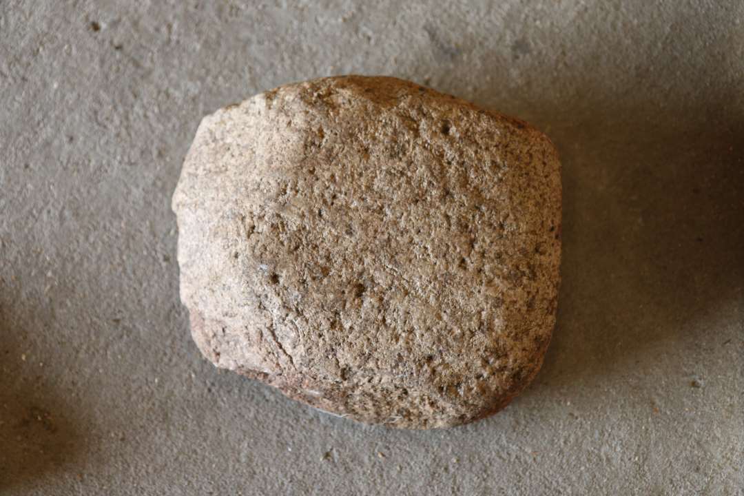 Løber, eller skubbe-sten til skubbekværn. Tydelige slidspor, der klart viser, at den hører sammen med skubbekværn x01. Ca. 20x23x10 cm.