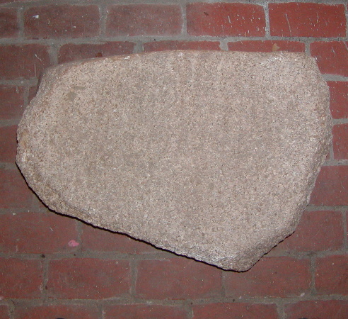 Stor sten, ca. 70x30-50x<20 cm. Hele den ene fladside har spor efter slibning. Således er denne side svagt hulet.