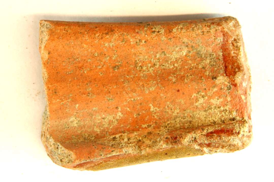 1 fragment af skaftformet hank af flad oval tværsnitsform med to brede furer på oversiden rødbrændt lergods med pletter af klar blyglasur, gruppe 1.