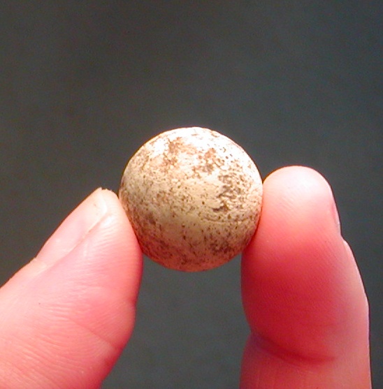 Rund kugle af blødt  hvidtbrændt ler. Ca. 1,8 cm diameter. Legetøjskugle.