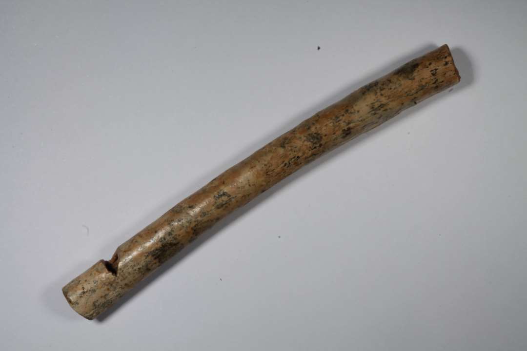 Fragment af fløjte af smal, let buet rørknogle. Længde: 8,4 cm.