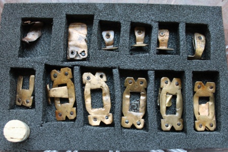 Bæltedele af bronze/kobber, seks hele og et halvt  beslag med rektangulær gennembrydning, 6 hængebeslag + div. fragmenter, samt et remendebeslag. Mål: fra 1,6-3,8 cm.

Parallel, se ASR 13x734