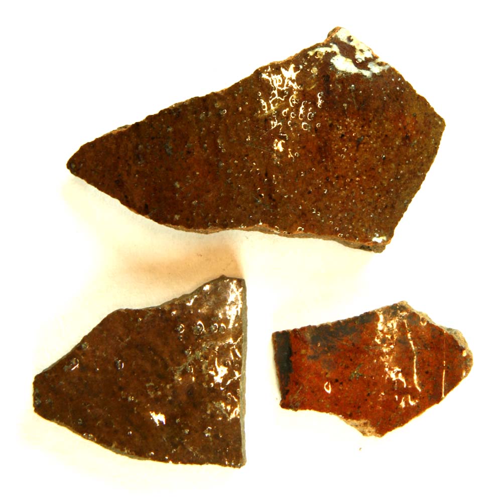 Tre bugskår fra kander af rødbrændt og rødbrunligt lergods med klar til grønlig blyglasur på ydersiden og på enkelte pletvis på indersiden.