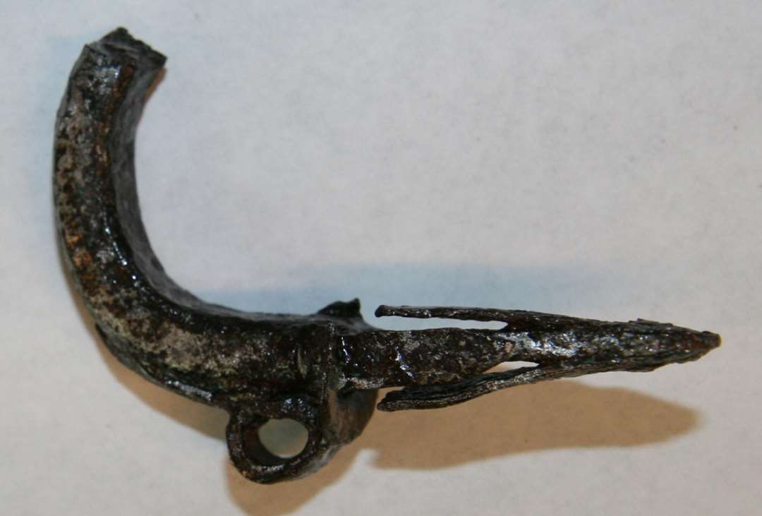 Fragment af låserigel af jern med kraftig bøjle. Spor efter CU ses, måske fra lodning. Største længde 4 cm.