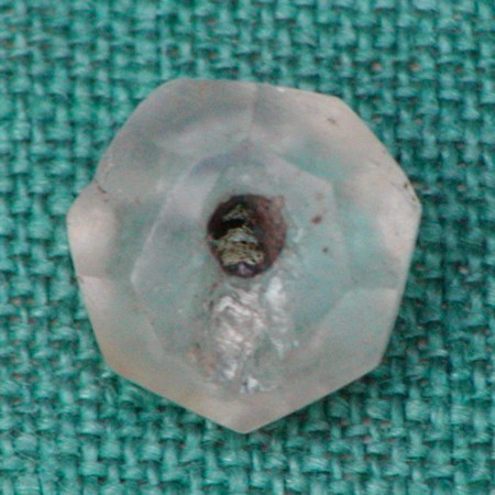 Hel perle. Lidt uregelmæssig. Slebet i mange små facetter. Største diameter: 0,9 cm. Tykkelse: 0,35 - 0,6 cm.