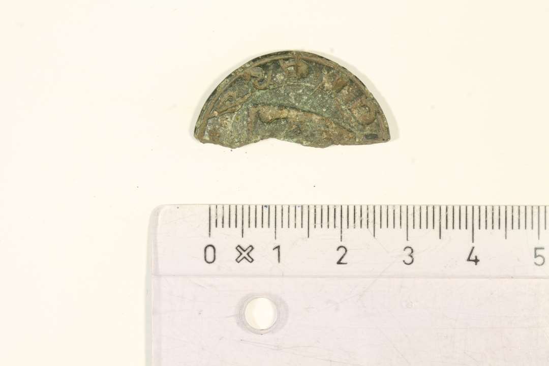 ½ Seglstampe. diameter: ca 3,1 cm. En halv seglstampe af bronze fra middelalderen. Den bevarede del af omskriften læser 'CLESØ', formentlig 'Mikkelsøn' eller 'Niklassøn'. Stampen har formentlig været dekoreret med et våbenskjold.Der ses oversiden af et skjold i motivfeltet. 
