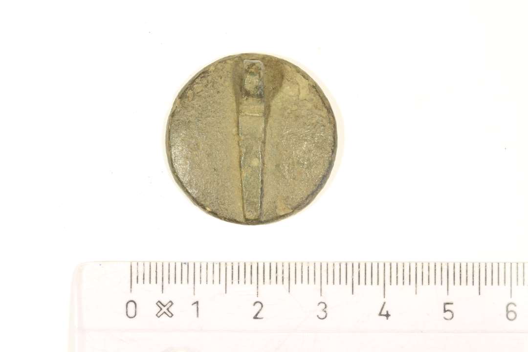 En seglstampe af bronze fra middelalderen med et skjold dekoreret, hvori der sidder en økse og et andet våben. Omskriften læser 'S'THRUGILLI BRUDI' hvilket oversat til dansk betyder at seglet har tilhørt Troels Bryde. En bryde var en forvalter i middelalderen. Diameter: 2,7 cm. Med øsken bagpå