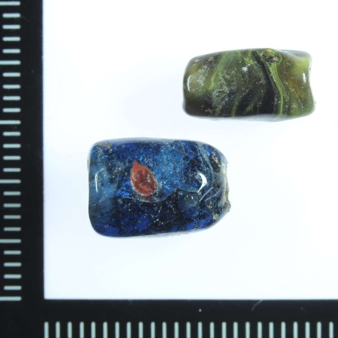 En klar blå med røde prikker
En mørk olivengrøn med iblandet gul. Sjældent eksempel på et hulglasskår der er direkte omsmeltet og anvendt til en perle? Sammenlign med f.eks. hulglasskår ASR 2360x138, id 200166655.