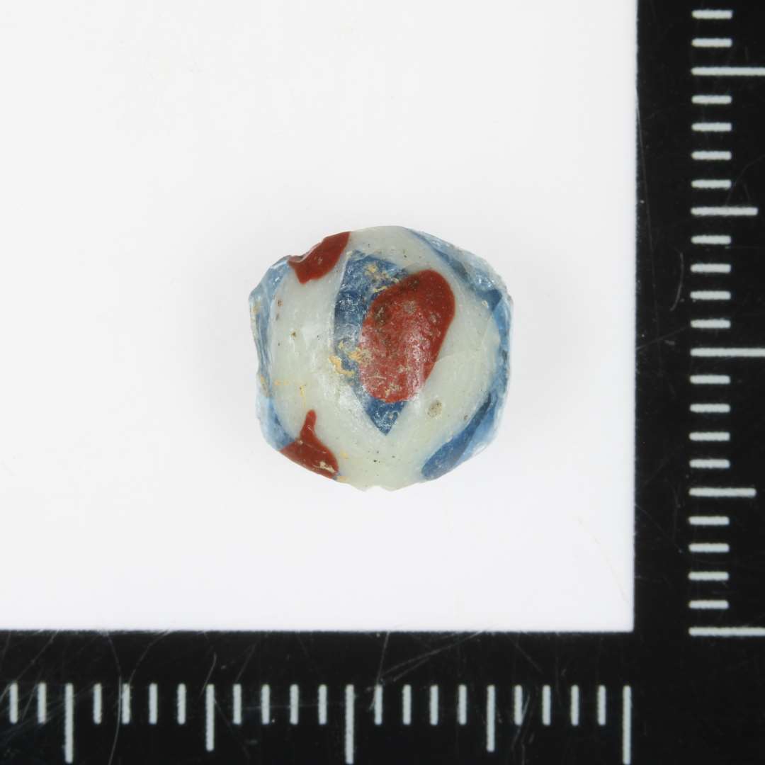 Fragment af blå perle med hvid og rød ornamentering. 