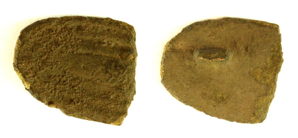 Fragment af trefliget fibel. Rest af nålefæste på bagside, stregornamentik på overside. Mål: 18 x 21 mm.