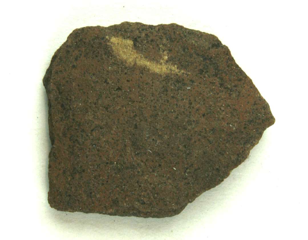 Bug- eller bundskår af finslemmet porøst lergods med grålig kærne og brunlig yder- og inderside. Denne fremtræder med stærkt afglattede partier og striber.