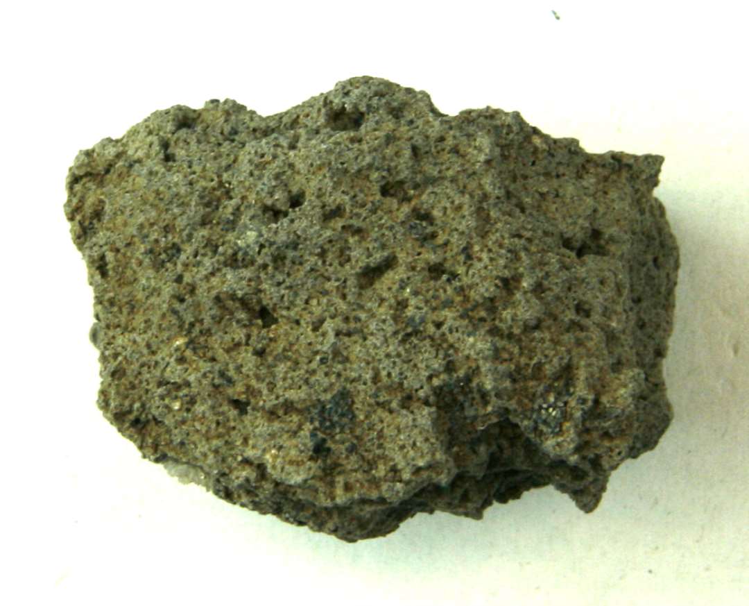 Uregelmæssigt, kantet fragment af gråligt basaltlava, største mål: 3,1 x 3,5 x ca. 5 cm.