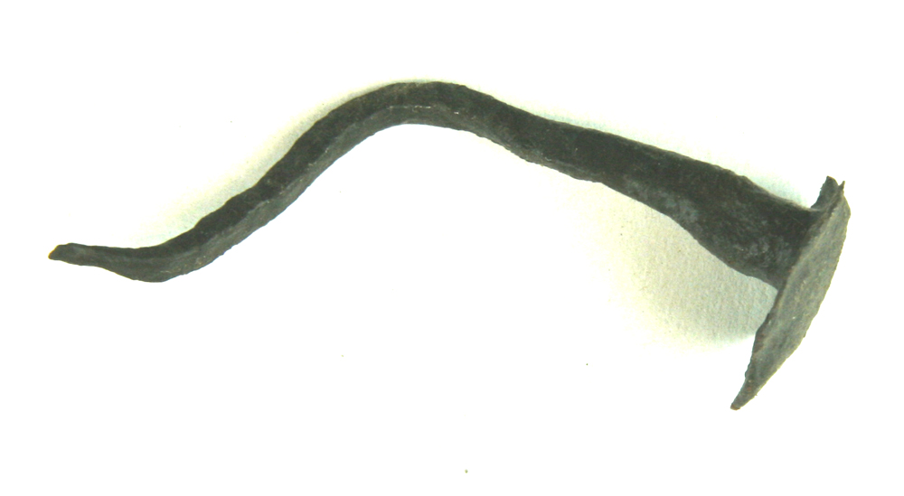 Håndsmedet jernsøm bøjet på midten og i spidsen. Sømmet er forsynet med et fladhvælvet ovalt hoved ca. 2,35 x 2,8 cm. Største længde: ca. 6,7 cm.