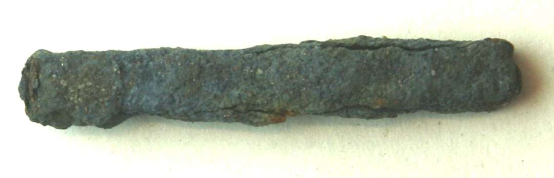 Fragment af jernstang af kvadratisk tværsnitsform, ca. 0,8 x 0,8 cm. lige overbrudt i begge ender.  Længde: 5,6 cm.