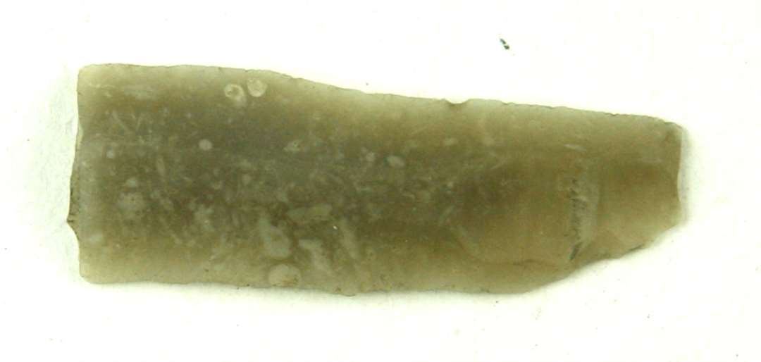 Fragment af flintflække af lysegrålig flint. Fragmentet udgør flækkens tilspidsende, afbrudte ende. Længde: 4,8 cm. Bredde: ca. 1,7 cm.