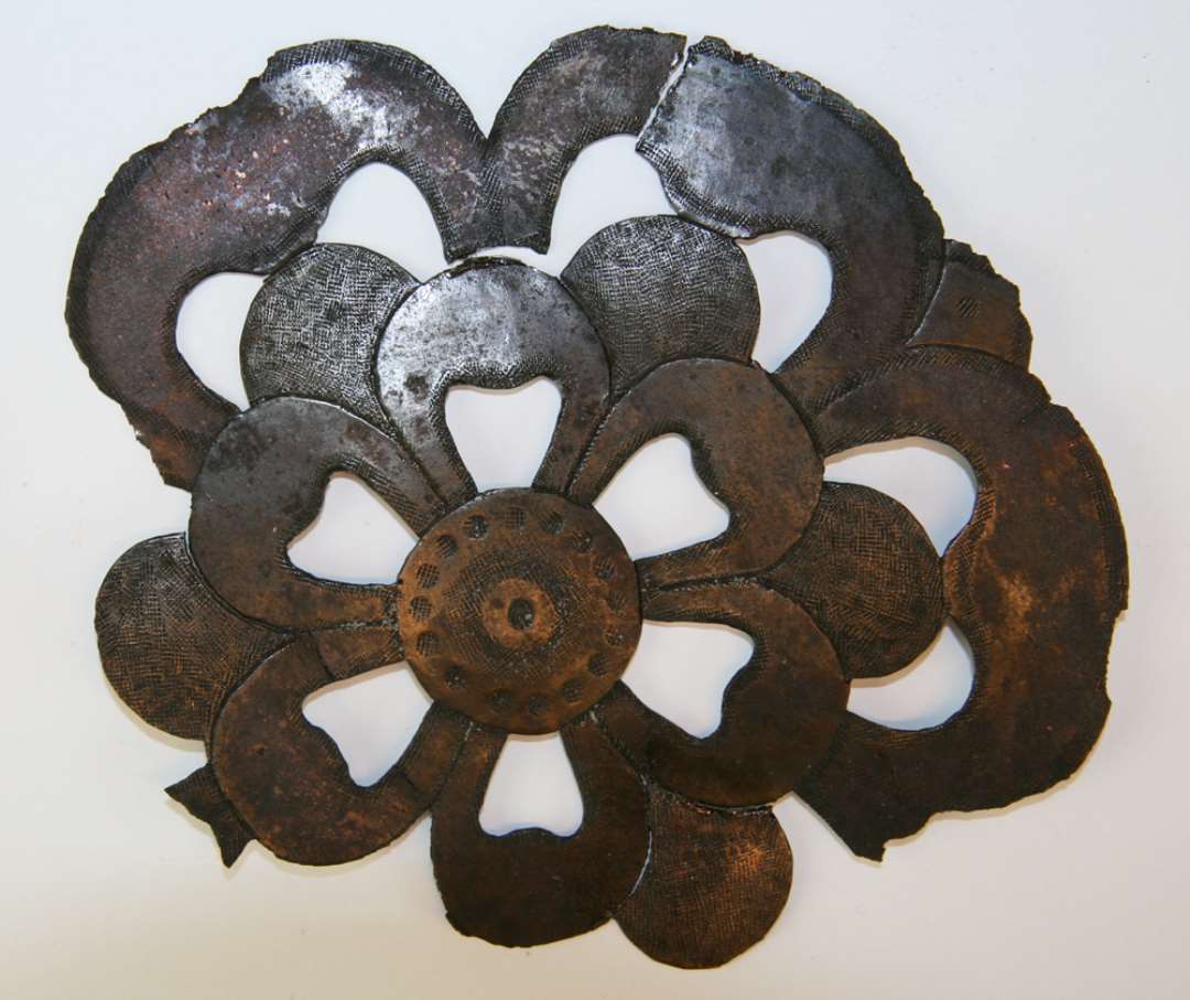 Fragment af stiliseret dobbelt blomsterroset udført i gennembrudt arbejde i tynd bronzeplade. Stykket er forsynet med meget fint punslingsarbejde på oversiden. Største mål : 13,6 x 11,8 cm.