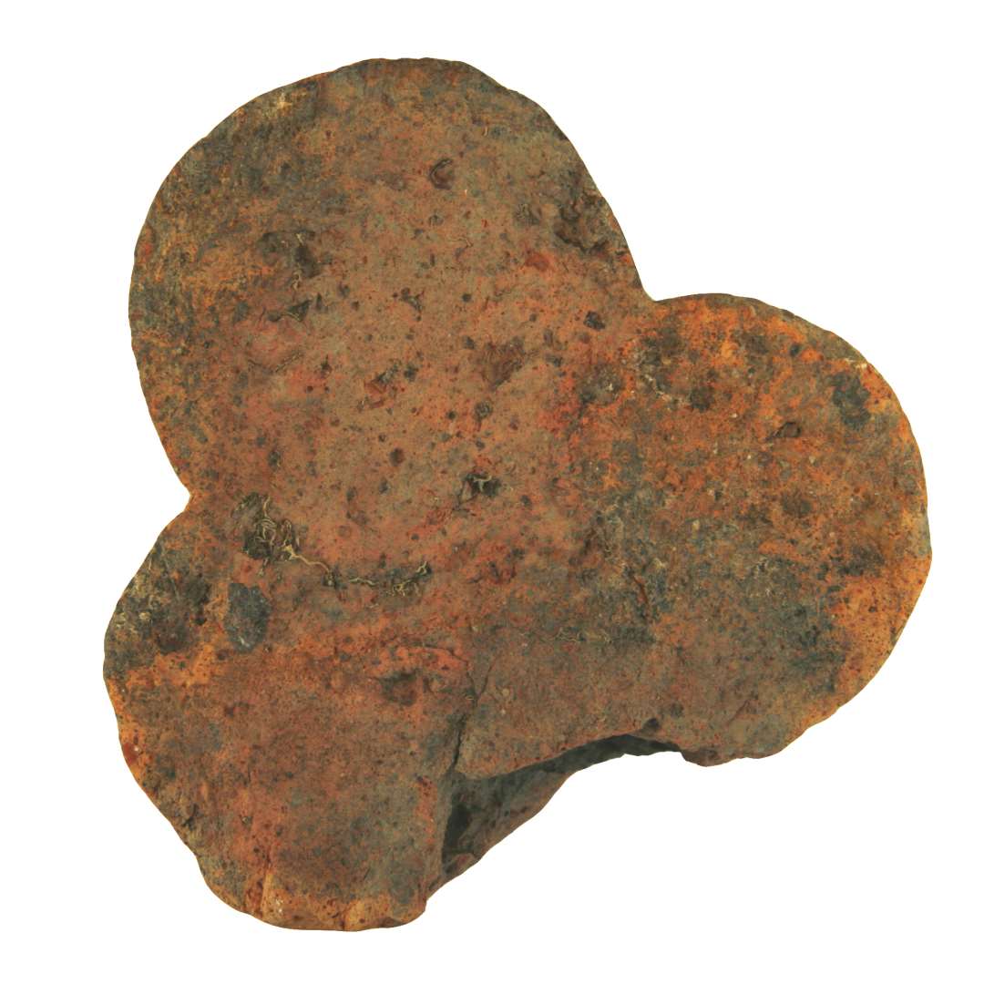 Ribbesten af rødbrændt ler. Trekløverbladsformet del bevaret, resten mangler. Højde: 7,7 cm. Bredde: 13,0 cm. Nuværende længde: 13,0 cm.