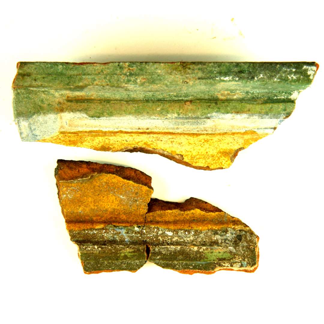 Fragment af polykrom gesimskakkel, sammenlimet af 4 skår. Dekoreret som forrige. På fragmentet ses de to skæggede brødre, som kaster den skægløse Josef i brønden. Profileret ramme og del af øvre skrå stykke. Største mål: 9,5 cm.