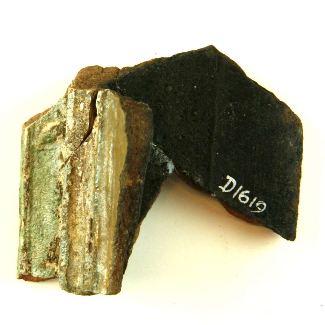 Fragment af polykrom gesimskakkel. Stump af midterfledt uden relif og den profilerede ramme. Sammenlimet af D1572, D1903, D1619. Største mål: 7,5 cm.