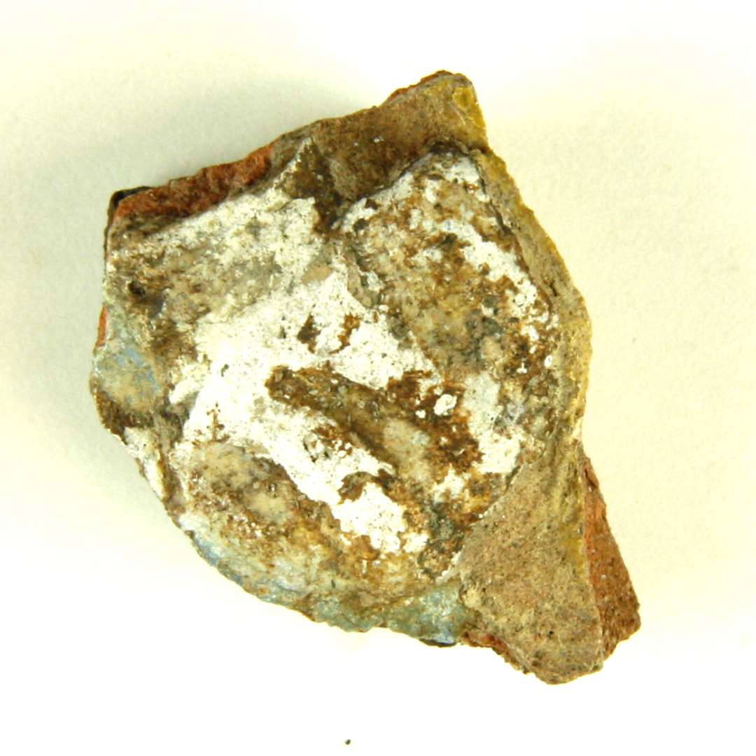 Fragment af polykrom, lodret kakkel. Del af motiv med dame i renæssancedragt: Hvid puf fra ærme.Største mål: 3 cm.