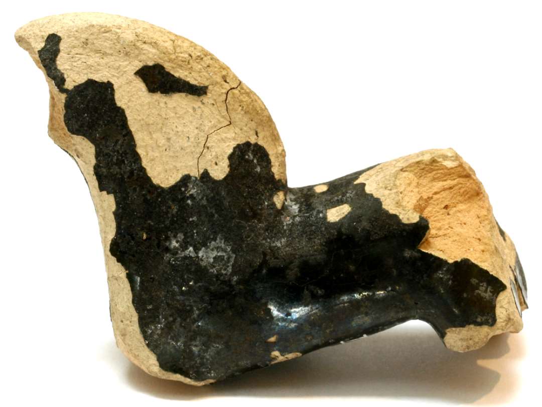En fragmenteret, stiliseret hestefigur af ret porøs, grågullig, finslemmet lermasse, forsynet med en nu delvis afskallet, dybgrønlig blyglasur. Figuren har en kort, smal krop med stejlt oprejst hals med en overdimensioneret, bred, fladtrykt manke, som i profil danner en kvartcirkel. Hestens hoved, hale, forben og tildels begge bagben er afbrækkede. I undersiden af hestens bug findes et ca. 2 cm. dybt konisk indboret hul med mundingsdiameter på 0,7 cm. Største længde: 4,5 cm. Største tykkelse: 1,9 cm. Største højde: 5,1 cm.
