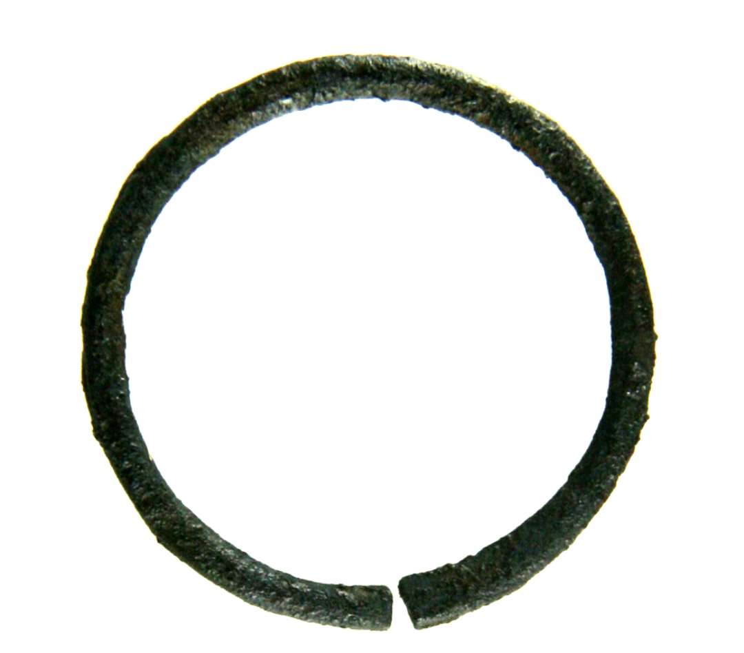 En ring af jern. Ydre diameter: 3,2 cm. tykkelse: 0,3 cm. Bøjet af at stykke tråd af halvcirkulært tværsnit, og hvor enderne mødes er ringen ikke samlet.  