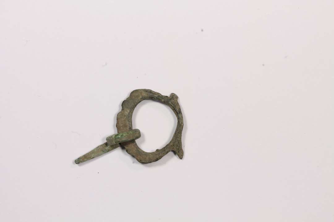 1 bronzespænde med tunget kant og bevaret torn. Meget spinkelt Diameter: ca 1,7 cm.