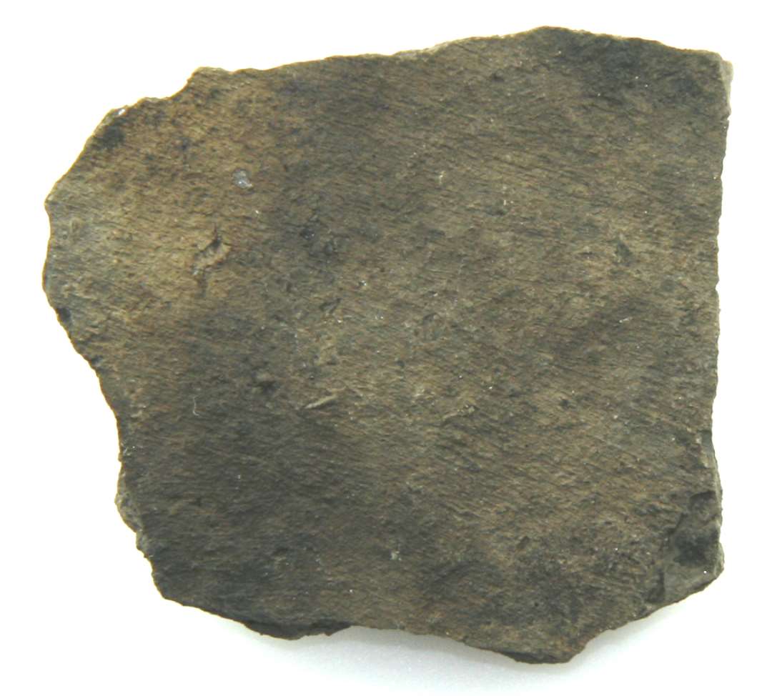 Side- eller bundskår af gråbrændt lergods med sodlag på indersiden, antagelig fra kuglepottekar.