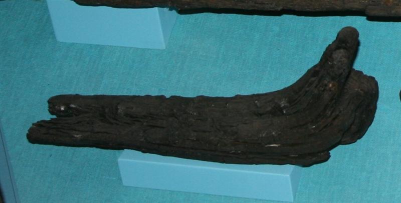 Skibsknæ af egetræ tildannet af en gren hvis naturlige krumning er udnyttet til knæets vinkelbøjede form. Set fra siden danner knæets arme på bagsiden en stump vinkel i forhold til hinanden, medens de på forsiden danner en jævn elipseformet krumning. Forsidens kanter har en let affasning. Medens knæets ene arm har tynd langstrakt form, med dels en tværgående dels en langsgående indskæring på bagsiden. Knæets lange arm har to naglehuller, det ene ca. 2,5 cm. i diameter ca. 7 cm. fra armens ende, det andet delvis bevaret i stykkets endekant. I knæets korte arm findes kun en delvis bevaret gennemboring ca. 2,5 cm. i diameter, den anden isiddende glat nagle ca. 2 cm. i diameter. Gennemboringen er anbragt således at medens de på ydersiden tangerer hinanden er der en afstand imellem dem på bagsiden. Stykkets største længde: 37 cm. Største bredde: ca. 14 cm. Største tykkelse: ca. 10 cm. Disse mål er taget i våd tilstand.
