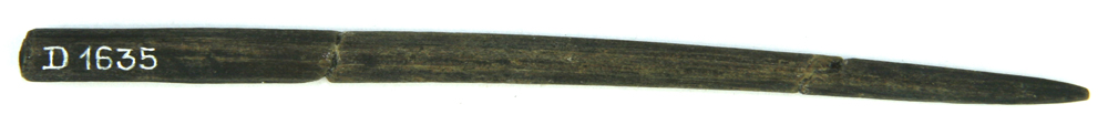 1 tynd, tilspidset træpind af bøg. Pølsepind? Med markante tilskæringsfacetter og let afrundet i den brede ende, på hvis flade, der findes et ikke afglattet brudar. Pinden er itubrudt ca. 3,5 cm. fra den bredde ende og ca. 3 cm. fra den spidse ende. Længde: 12 cm. Tykkelse: ca. 0,5 - 0,6 cm.