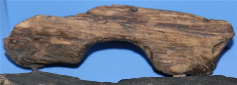 Fragmenteret trætøffel til en venstre fod, en såkaldt Holzpantine udført af blød løvtræsort. Tøflen har nærmest haft form som træskobund med højt klampeparti under hæl og fodblad, idet hælhøjden dog er 4,9 cm.  medens fodbladets højde er 3,8 cm. Hælen er meget smal ca. 4 cm. (Oprindelig dog ca. 4,5 cm. idet et stykke af hælindersiden mangler.) med jævnt afrundet bagparti. Vristen er stærkt indknebet til en bredde af ca. 3,3 cm. medens fodbladspartiet udvider sig i bredden, oval form med markant tilspidsning mod snuden, der er afbrudt, ligesom et større parti af tøflens yderside er borte. Ligeledes mangler en større del af fodbladets rand og klampens kant på tøflens inderside. Medens hælpartiet og tildels vristen har plan overside i en længde af ca. 8,5 cm. er fodbladspartiet ret kraftig nedadsvunget. På tøflens yderside i fodbladets vristindsvingninger findes rester af et mindst 5 cm. bredt tværgående læderbånd fastgjort med tre stærkt forrustede jernsøm. På tøflens modsatte tildels afbrudte inderside findes spor af to afbrudte jernsøm, der har fastholdt læderbåndet på denne side. På tøflens underside under fodbladet findes op mod fodbladsklampen et ejendommeligt 2 cm. bredt bælte hvor den iøvrigt meget omhyggeligt afglattede tøffel står med råt forarbejdet overflade. Største længde: 21 cm. Største bredde: 6,5 cm. Litteratur: A. Walcher von Moltheim: Bunte Hafner-keramik der Renaissance, Wien 1906, Tvl? XIX, Illustrationen viser person af lermed træsko. Fra Kakkeloven i Veste Hohen Salzburg, datering 1504.