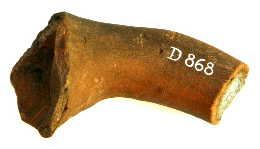 Fragment af kandehank af trind pølseform, rødbrunt lergods med grå skærv (uglaseret).