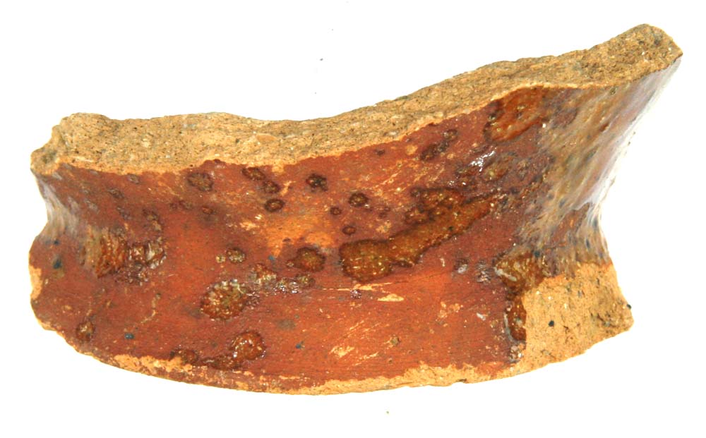 Bundskår af rødgult lergods fra kande med plan standflade, fremtrædende glat afrundet fodrand og udbuget korpusside. På ydersiden pletter af klar blyglasur. 