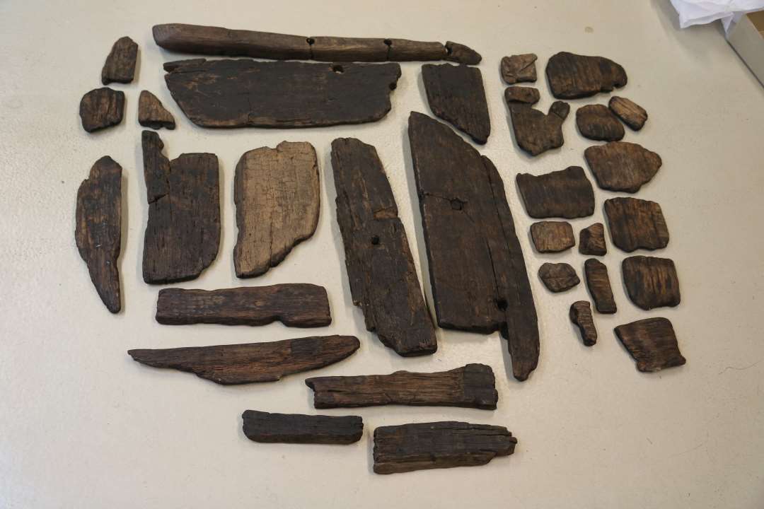 Mange små fragmenter af træ, der tilsammen danner en nærmest komplet karbund, incl. få dårligt bevarede stave kun i 10-15 cm. højde, 12-14 større stykker samt nogle smådele