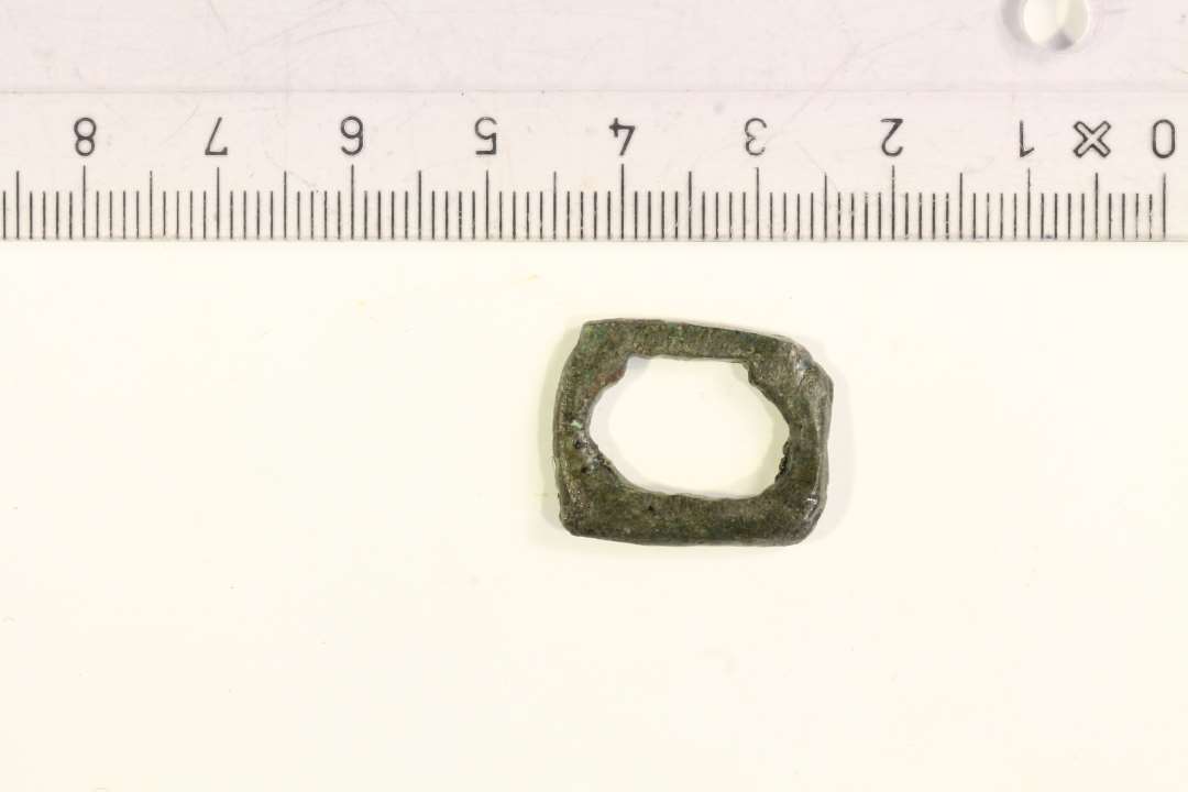 1 rektangulært lille remspænde af bronze, ca. 2 x 1,6 cm.