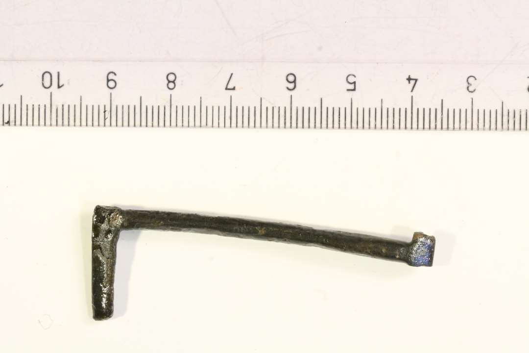 1 uidentificeret stangformet bronzesag, tydeligvis del af 'noget'. Vinkelformet. største mål: ca 5,5 cm.